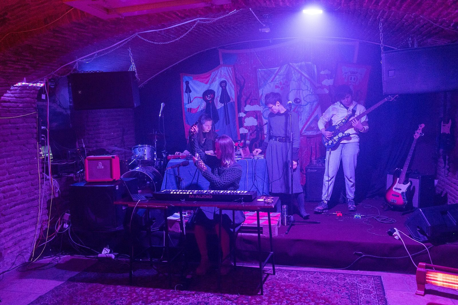 An indie band with keyboards and bass guitar playing under a brick-vaulted ceiling at Revolution Bar in Tbilisi