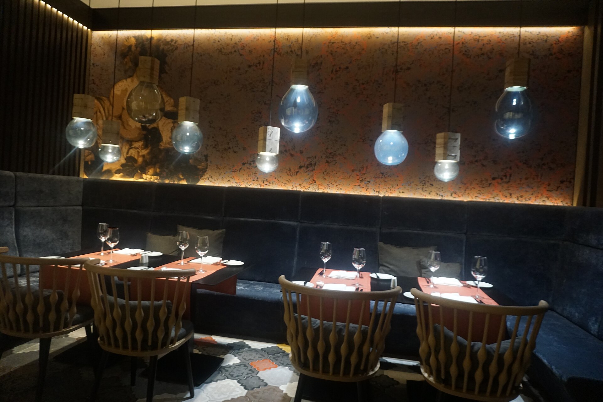 Tables set along a velvet banquette under glass pendant lamps at ATI, the restaurant of the Sheraton Grand Tbilisi Metechi Palace