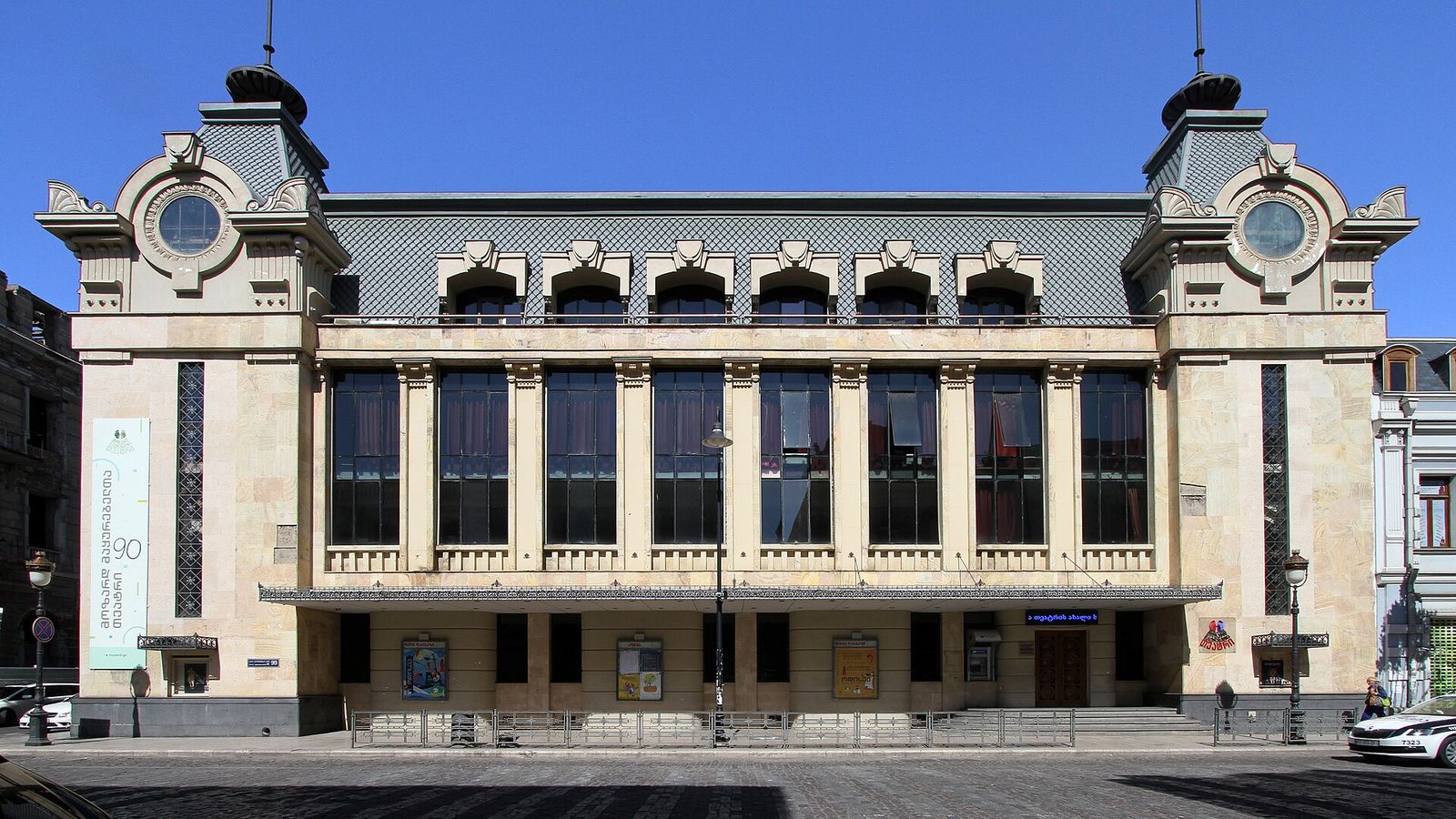 A cream early 20th-century facade with two corner turrets and round windows on Aghmashenebeli Avenue in Tbilisi