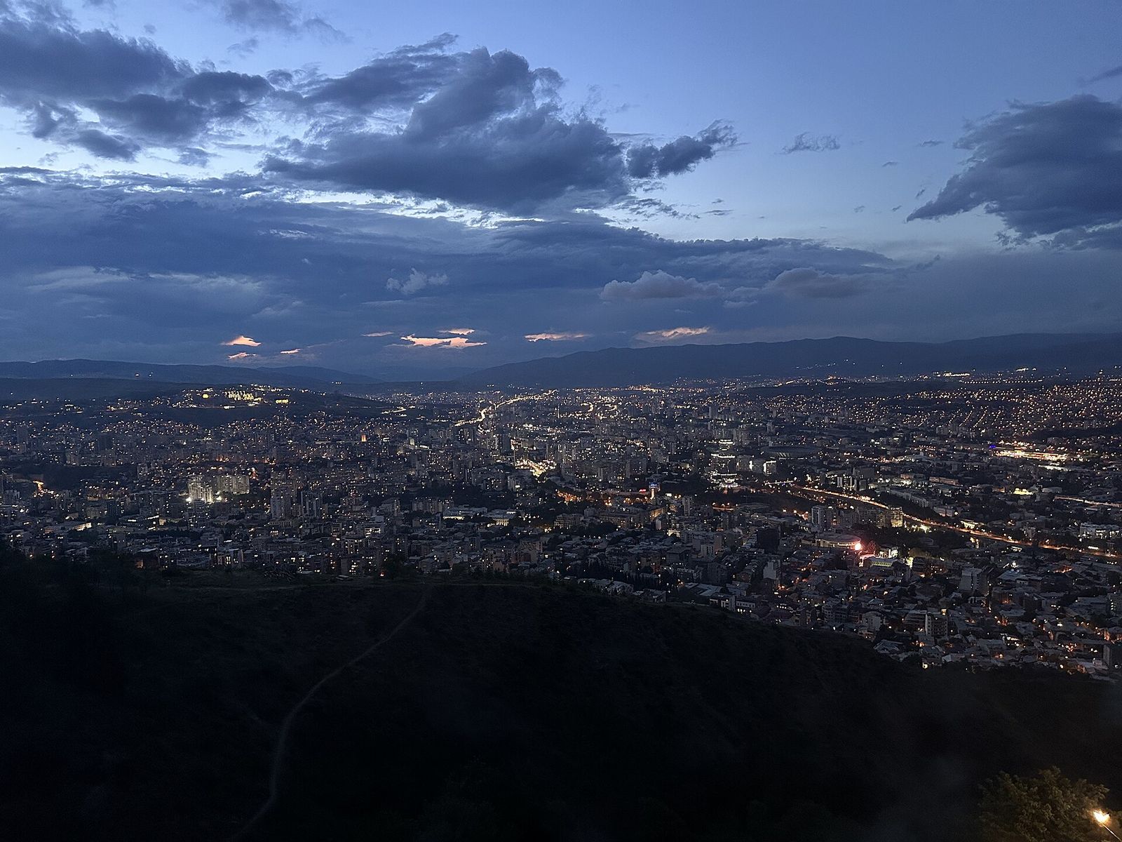 Tbilisi at dusk from Mtatsminda Park, the city lights spreading across the valley