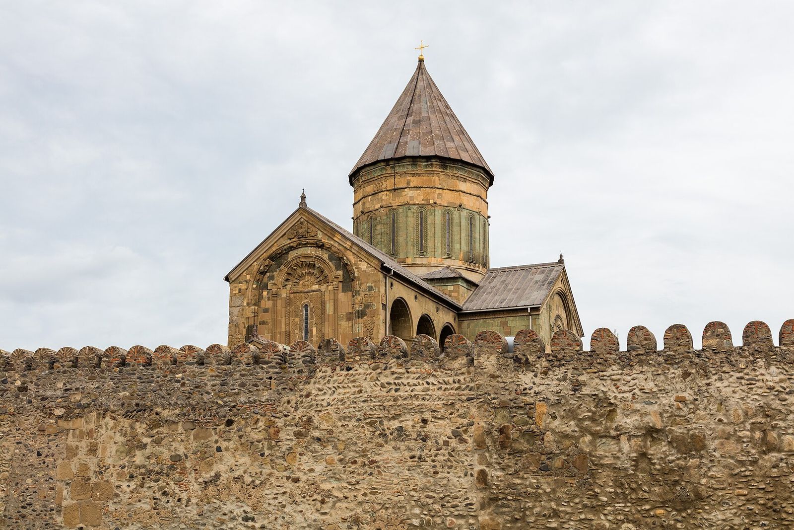 Svetitskhoveli Cathedral's dome and carved east facade rising above the stone fortress wall in Mtskheta