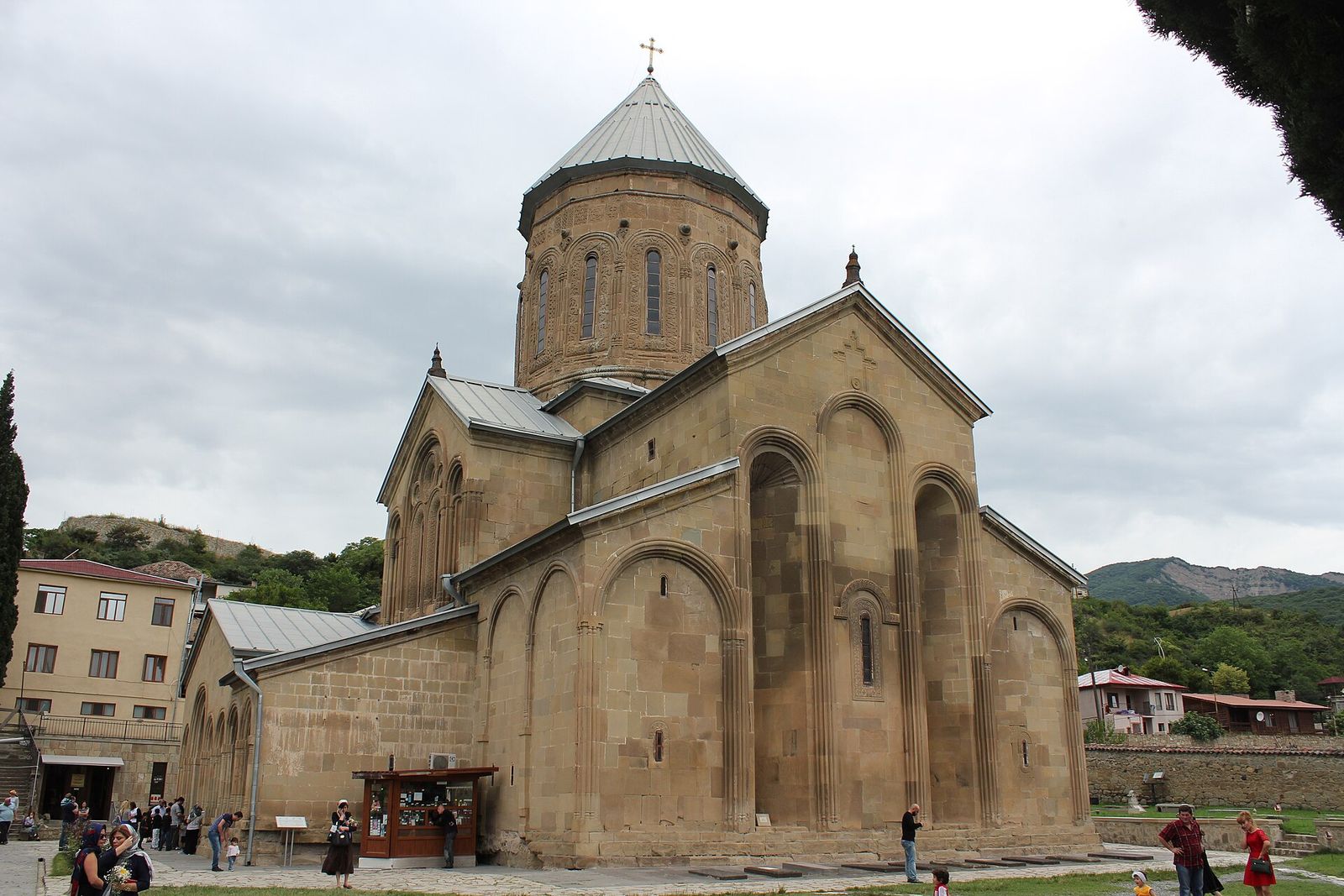The stone church of Samtavro Monastery in Mtskheta, with its tall drum and dome, and visitors in the courtyard