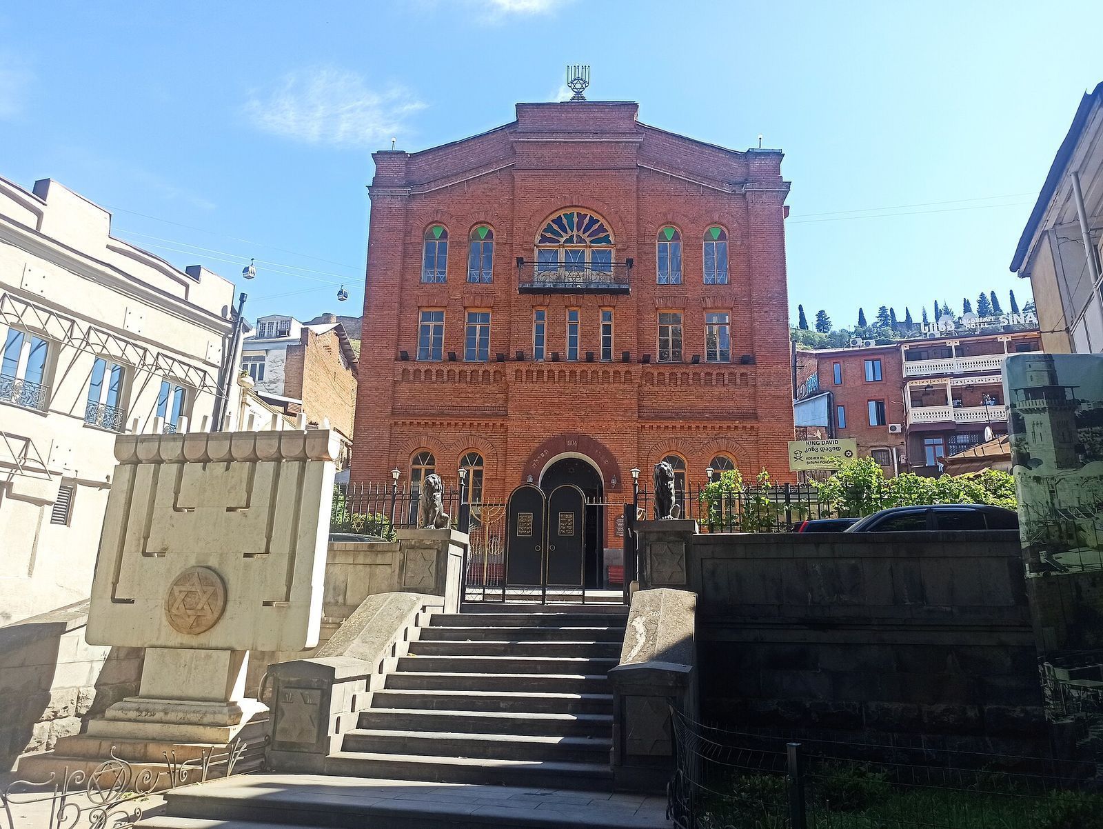 The red-brick facade of the Great Synagogue of Tbilisi, with stone steps and lions at its gate