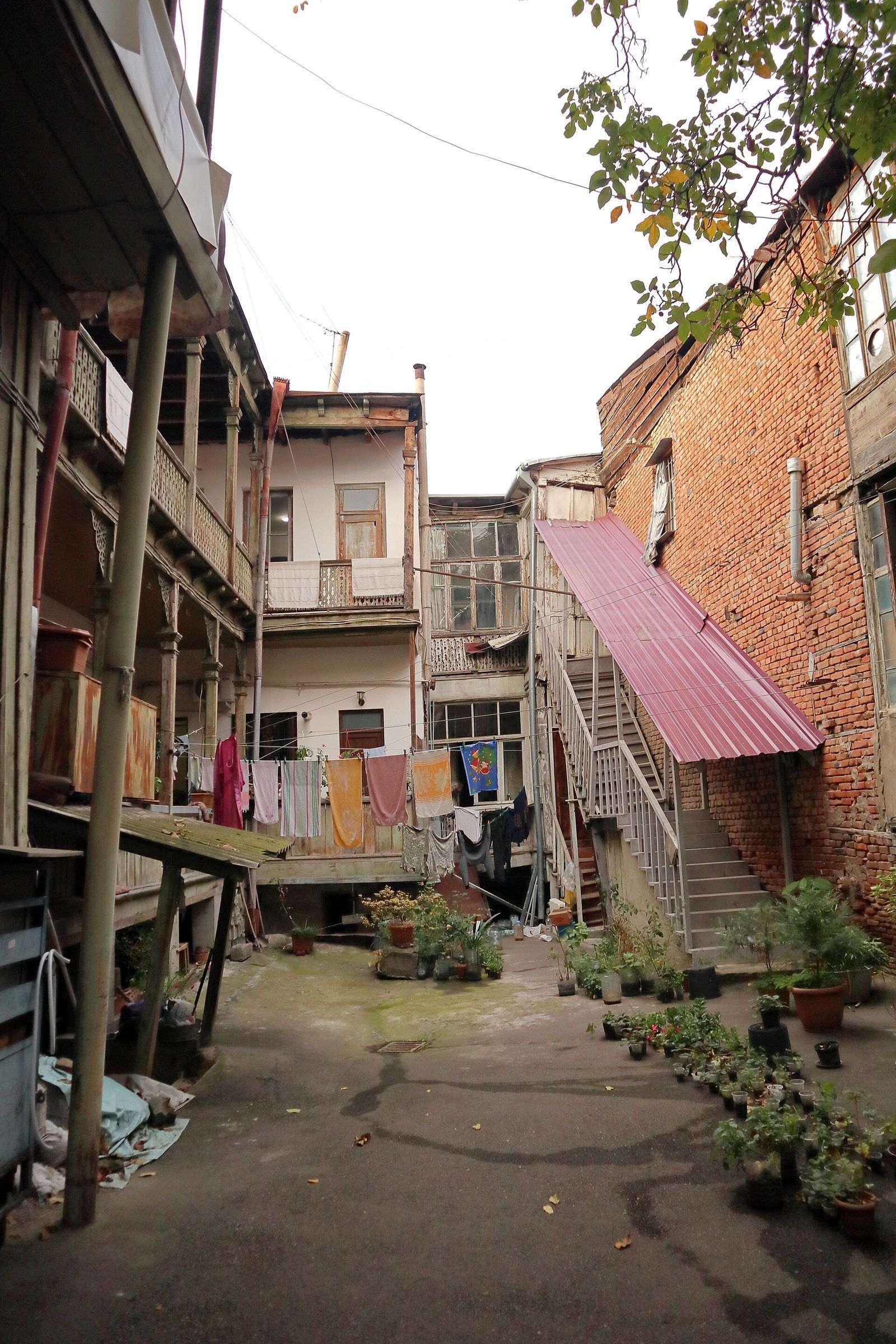 A courtyard in Kala with carved wooden balconies, washing lines and an outside staircase up the side of a brick house