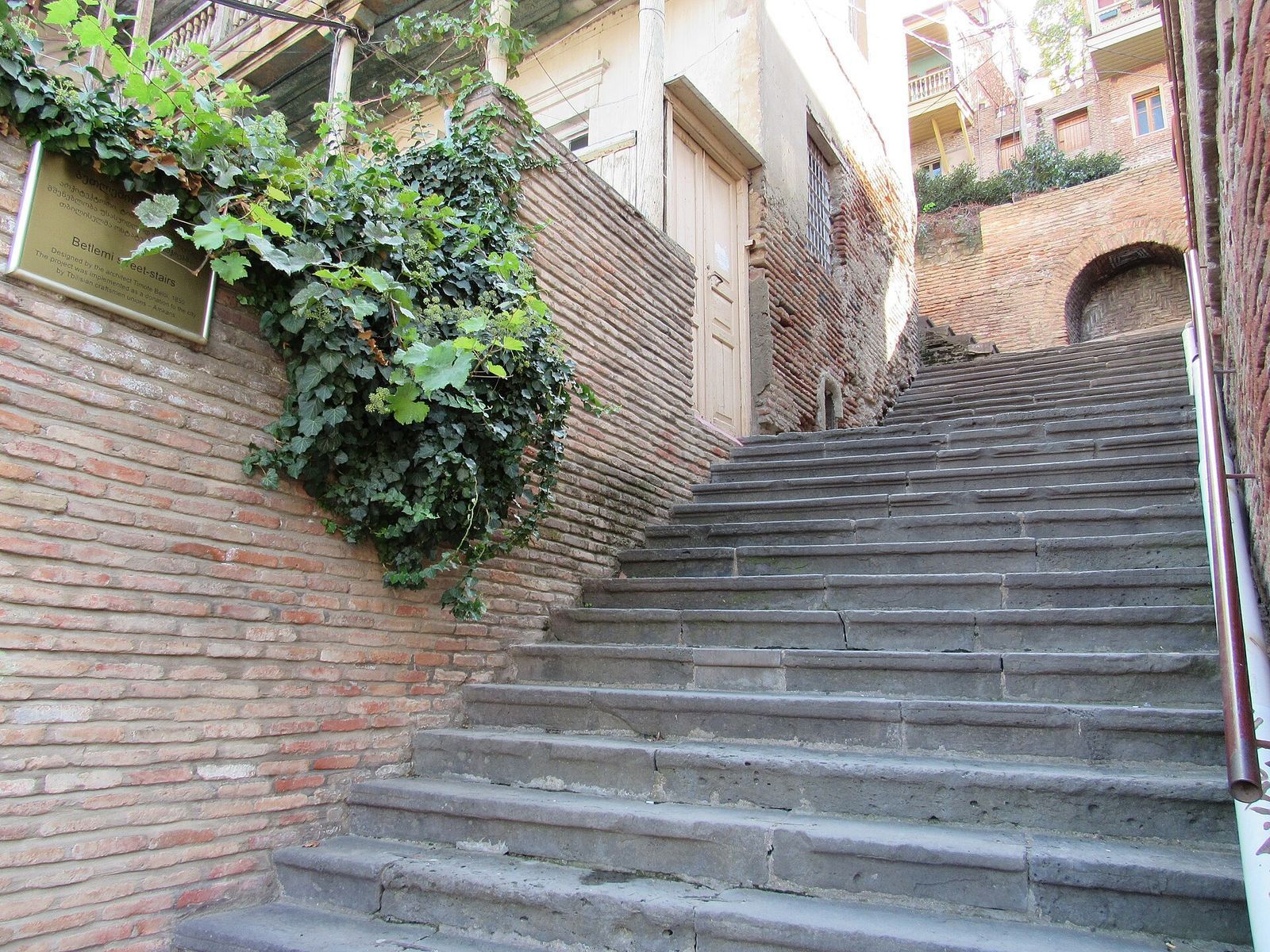 The Betlemi stairs climbing between old brick walls and ivy in Sololaki