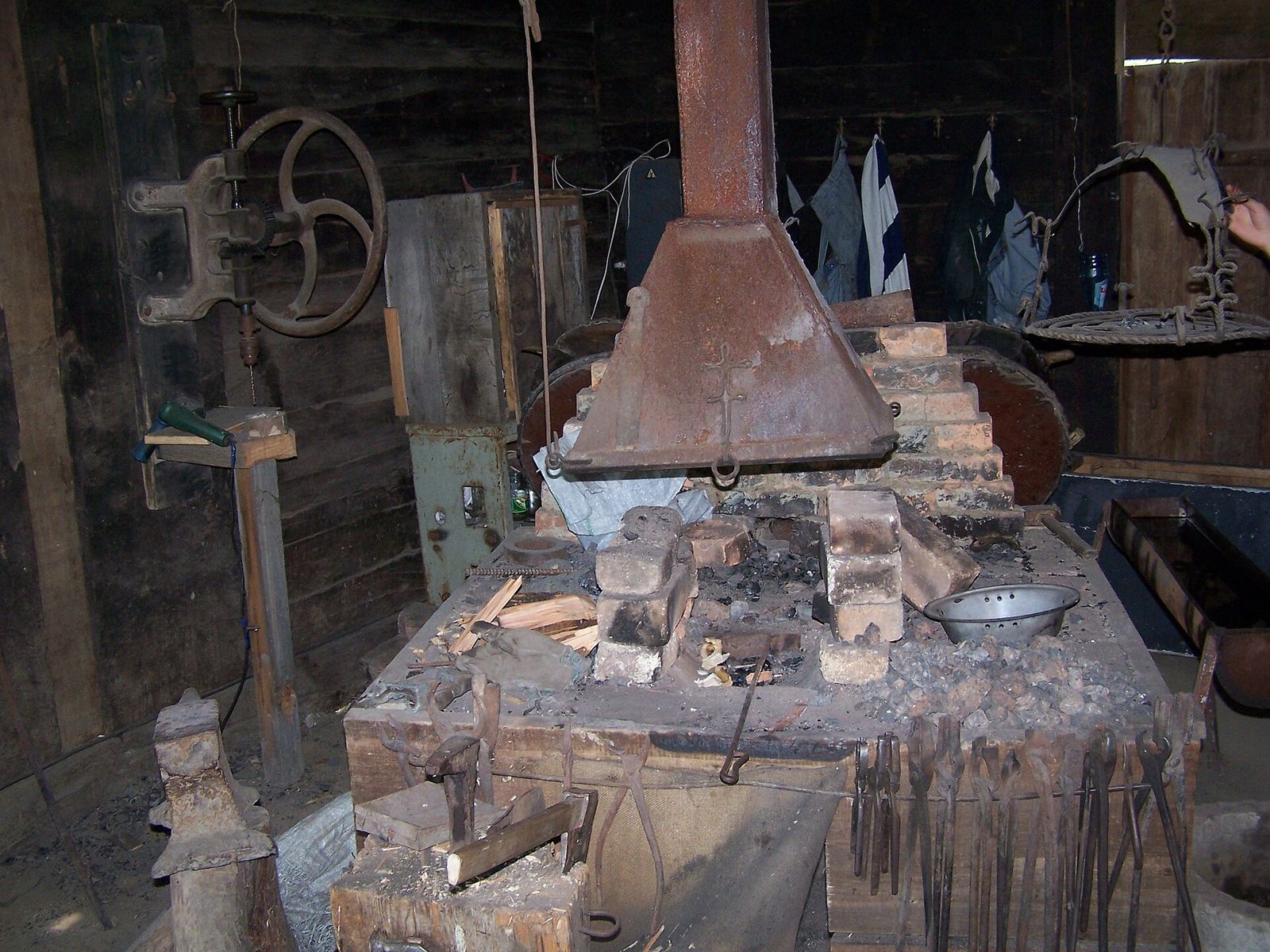 The village forge at the Open Air Museum of Ethnography, with its brick hearth, iron hood, anvil and a row of tongs