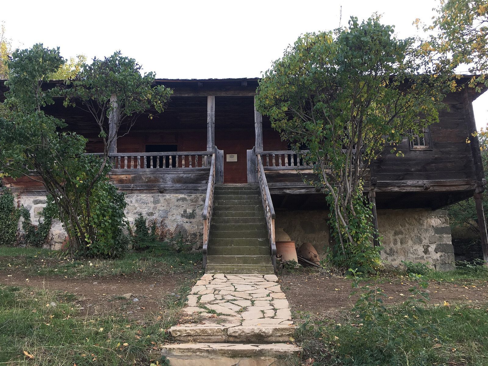 A two-story village house with a stone ground floor and a wooden veranda at the Open Air Museum of Ethnography in Tbilisi