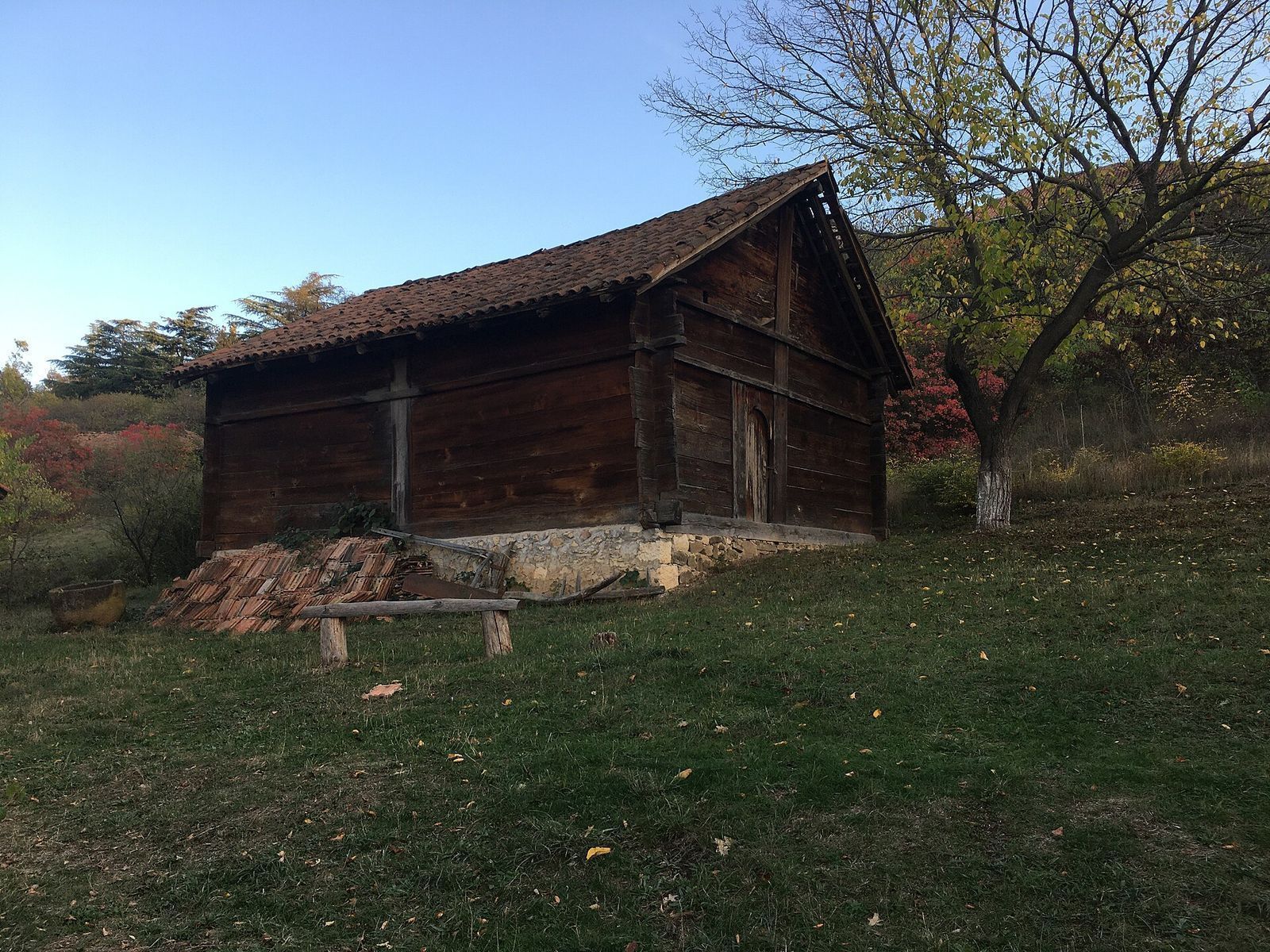 An old wooden farmhouse with a tiled roof on the grass at the Open Air Museum of Ethnography above Vake