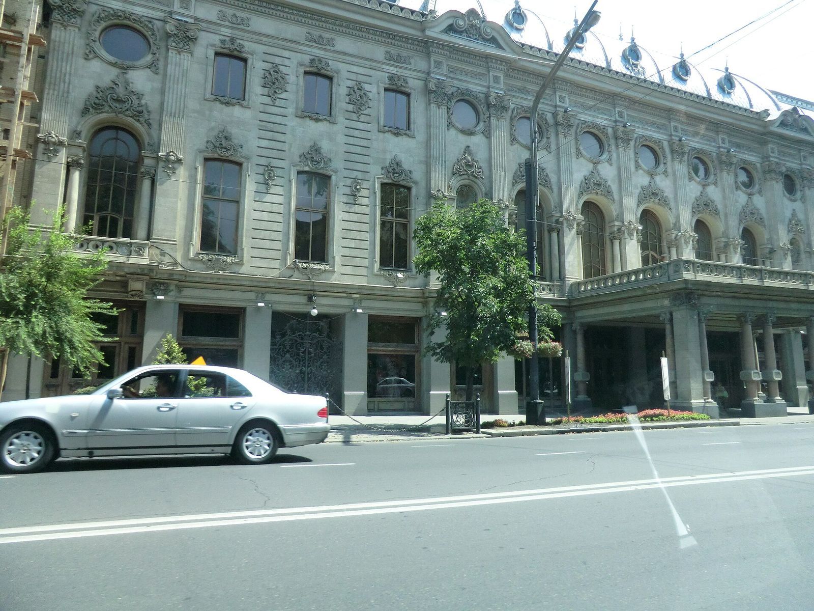 The ornate facade of the Rustaveli Theatre on Rustaveli Avenue, with its round windows, wrought-iron gate and columned porch
