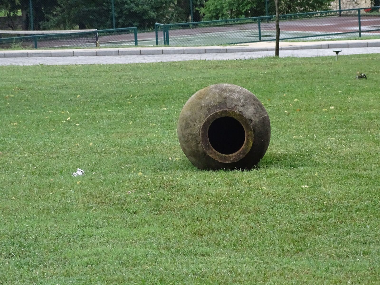 An old qvevri lying on its side on a lawn in Kvareli, Kakheti, its wide mouth facing the camera