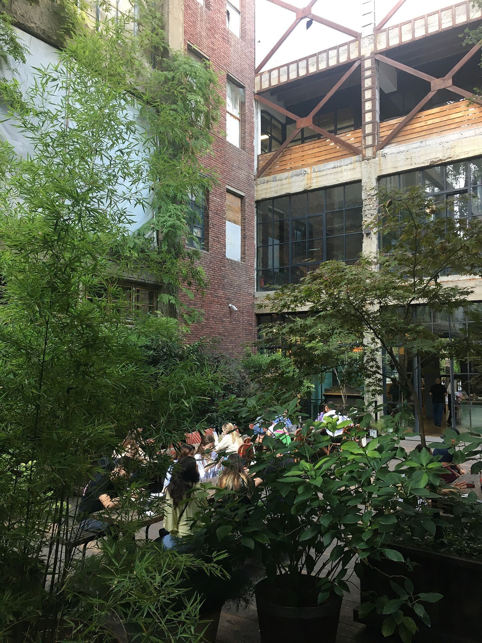 Tables among bamboo and potted trees in the courtyard of the old Soviet publishing house on Kostava Street, between its red brick and bare concrete wings