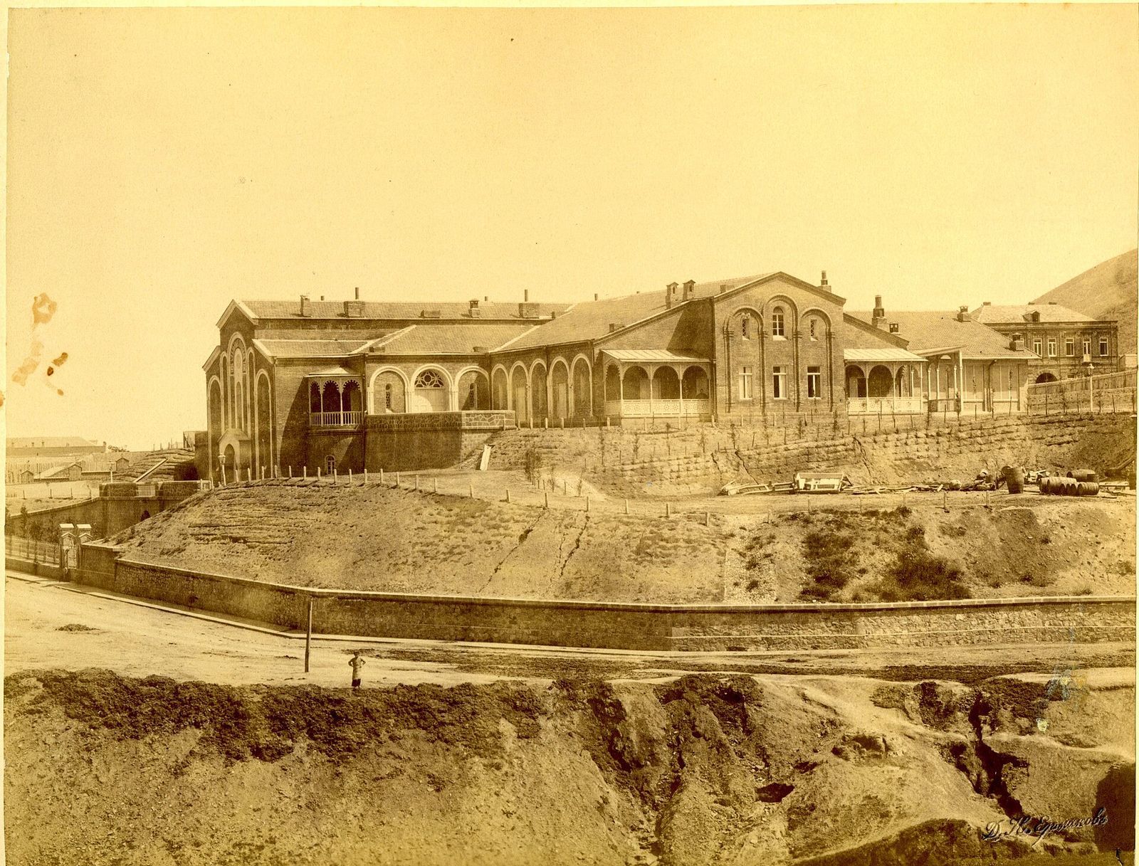Old sepia photograph of Wine Factory N1 on Vasil Petriashvili Street, its arched, church-like facades above a stone retaining wall