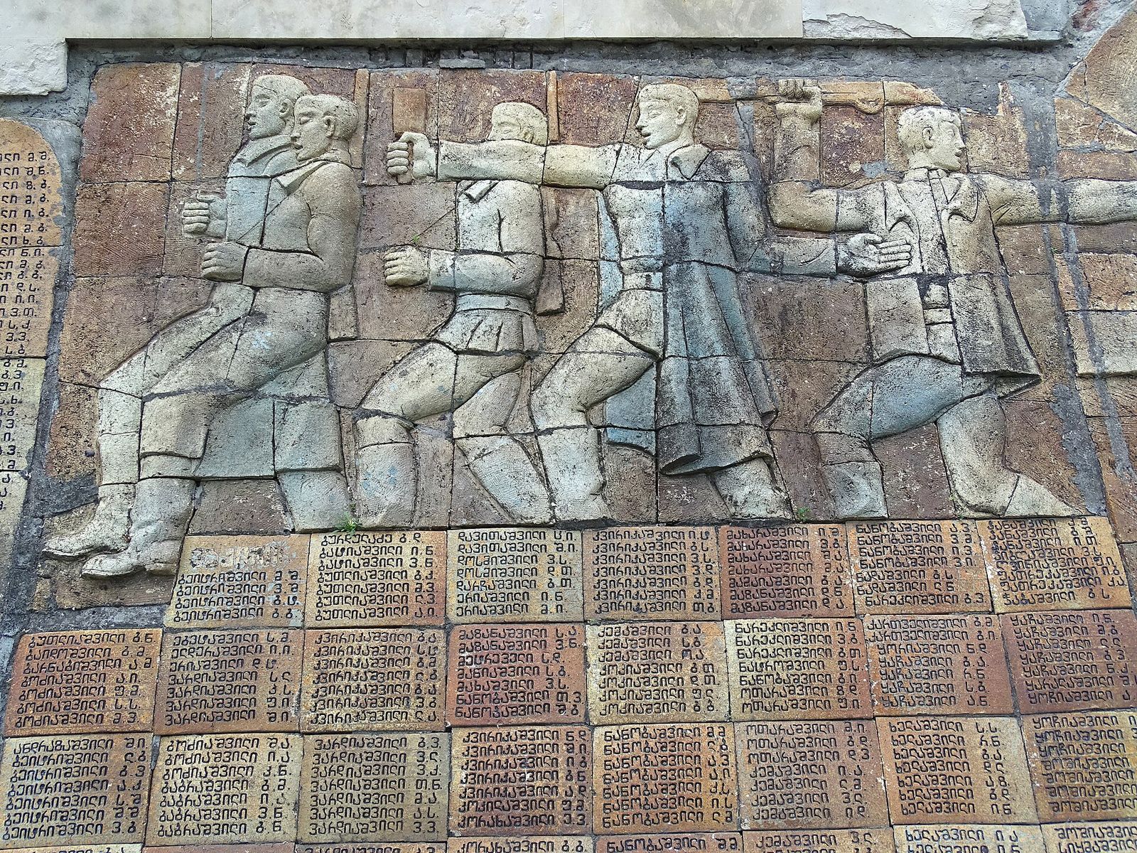 Bas-relief of marching figures above rows of carved names on the Second World War memorial in Sighnaghi