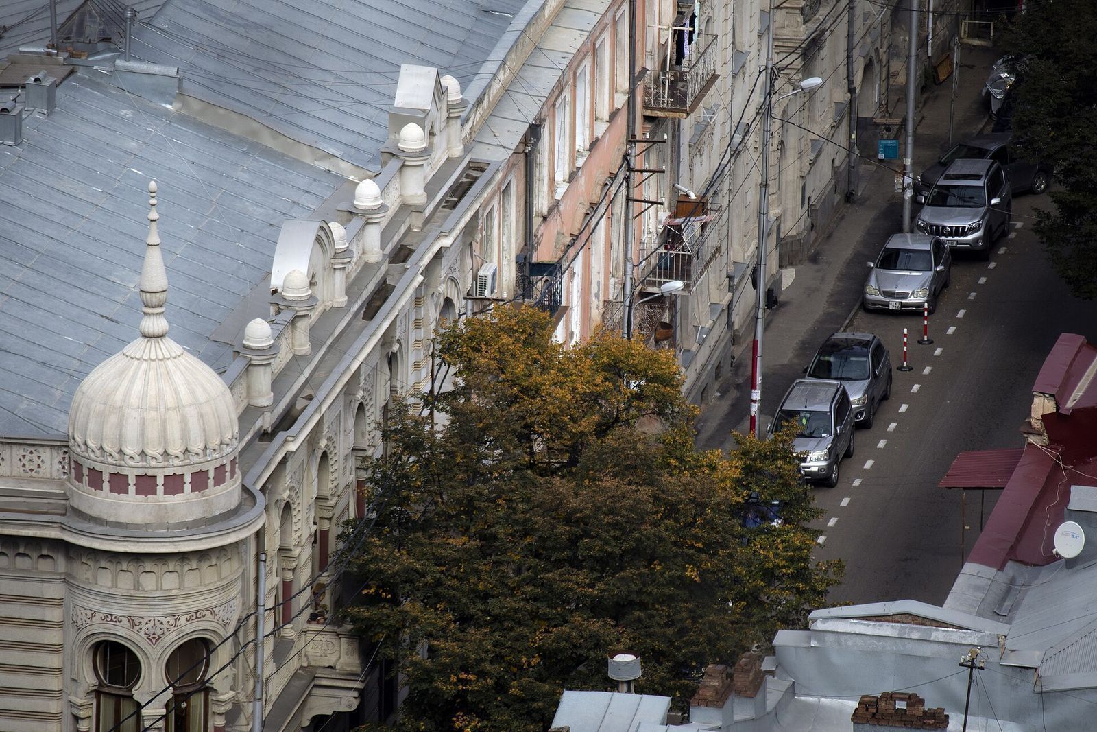 Ivane Machabeli Street in Sololaki seen from the Sololaki ridge, with a domed Moorish-style corner building and parked cars along the street