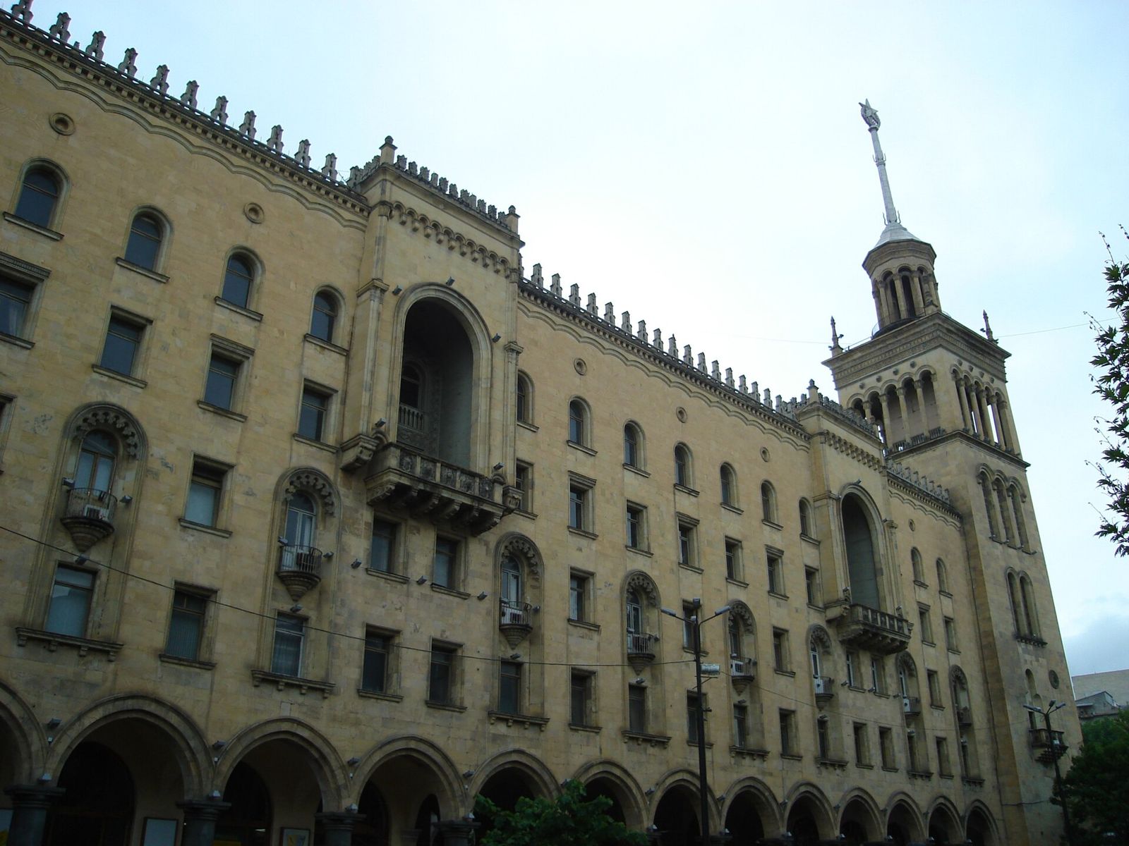 The Georgian Academy of Sciences on Rustaveli Avenue, with an arcade of stone arches along the ground floor and its spired tower on the corner