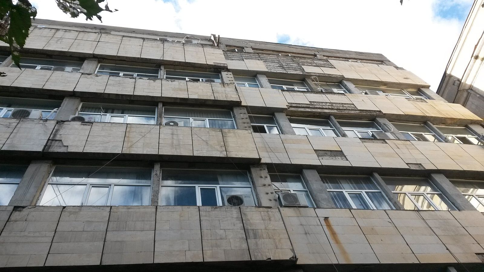 The concrete-panelled facade and long window bands of a Georgian Technical University building in Saburtalo, seen from below
