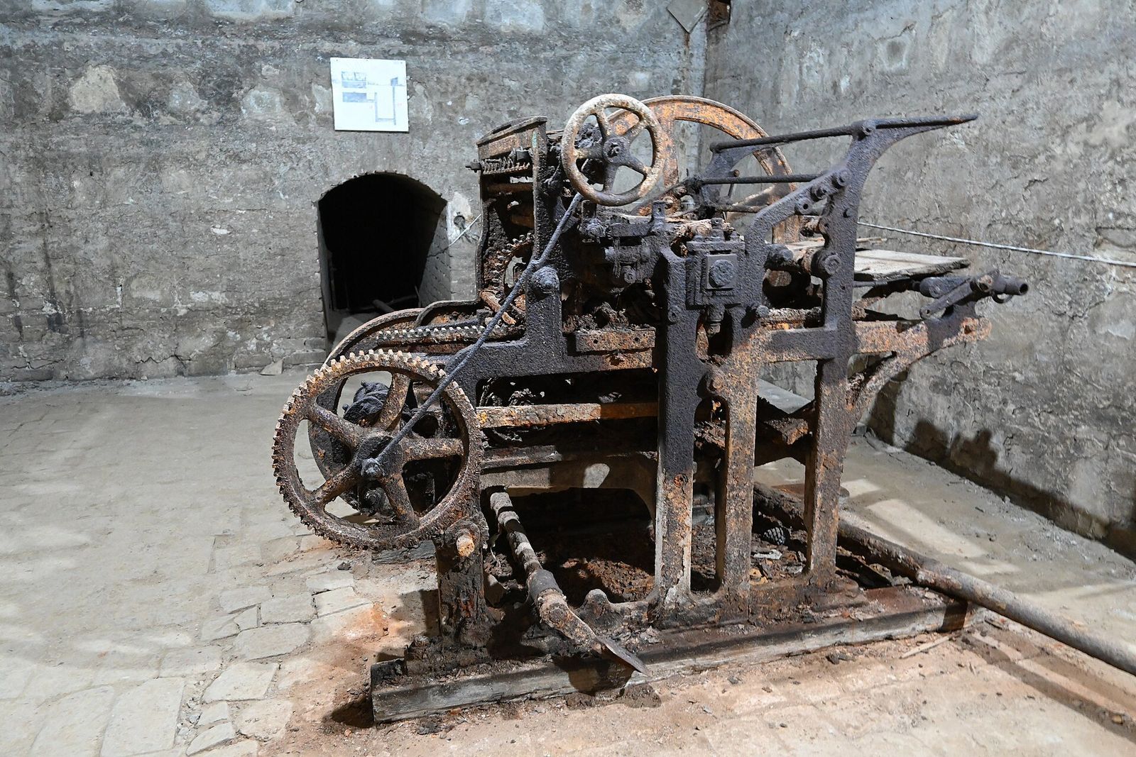 The rusted German printing press in the underground press room of Stalin's Underground Printing House, with the tunnel entrance behind it