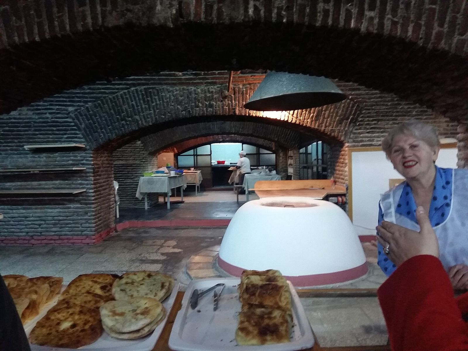 A basement bakery in Tbilisi with a round tone oven under brick arches and fresh khachapuri on the counter
