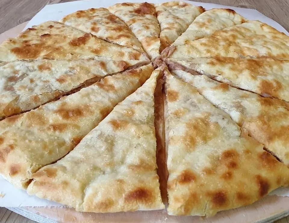 A round lobiani cut into wedges, with the mashed bean filling showing between the slices