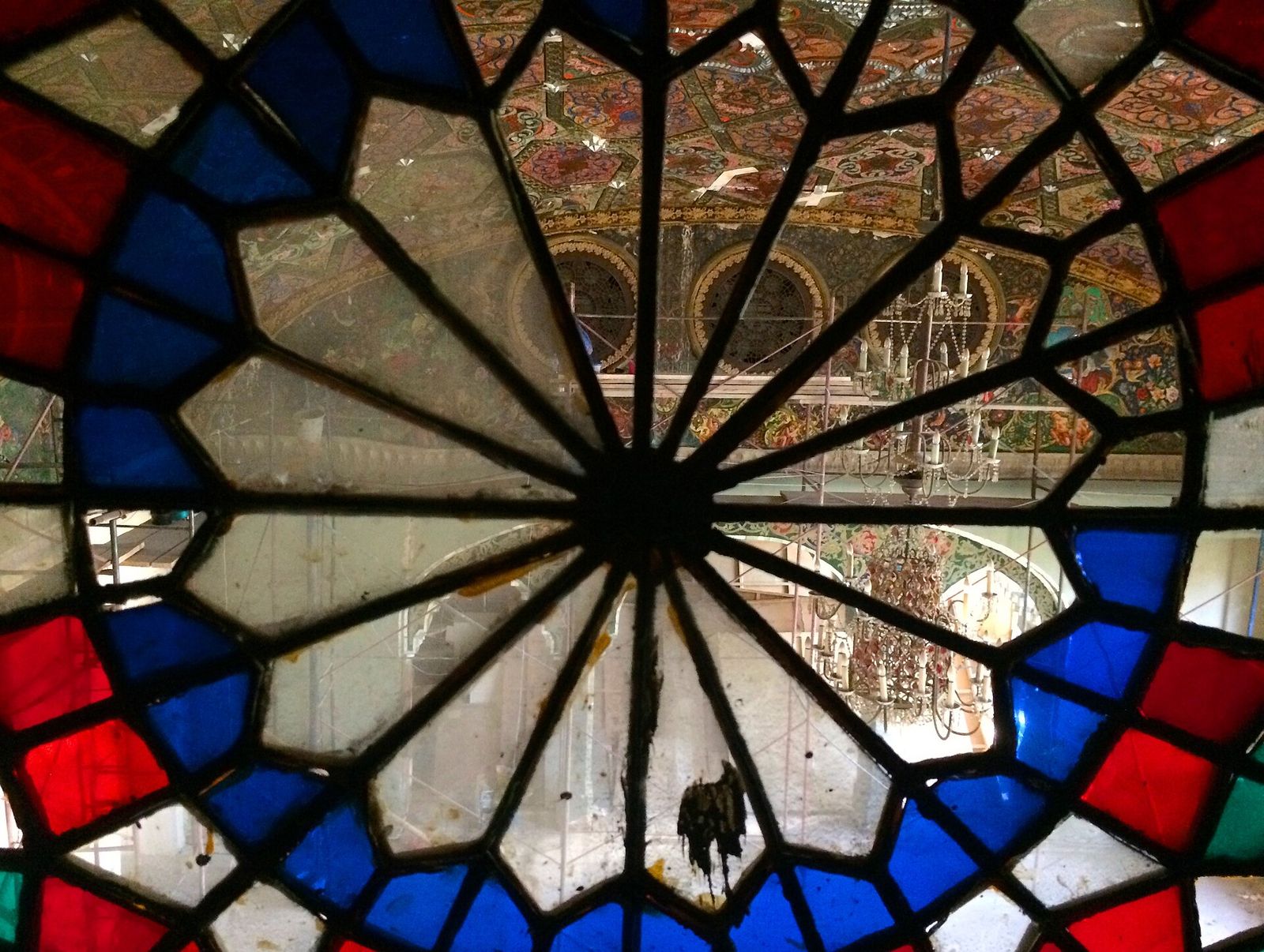 The Qajar painted ceiling and mirror-work arches of a hall at the Tbilisi State Academy of Arts, seen through a stained-glass window during restoration