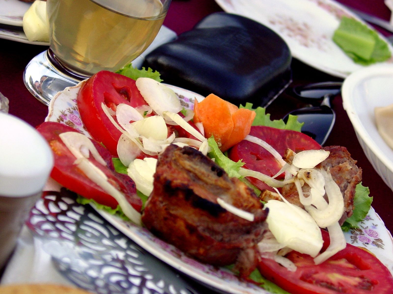 Mtsvadi, chunks of Georgian grilled meat served with sliced tomatoes and raw onion