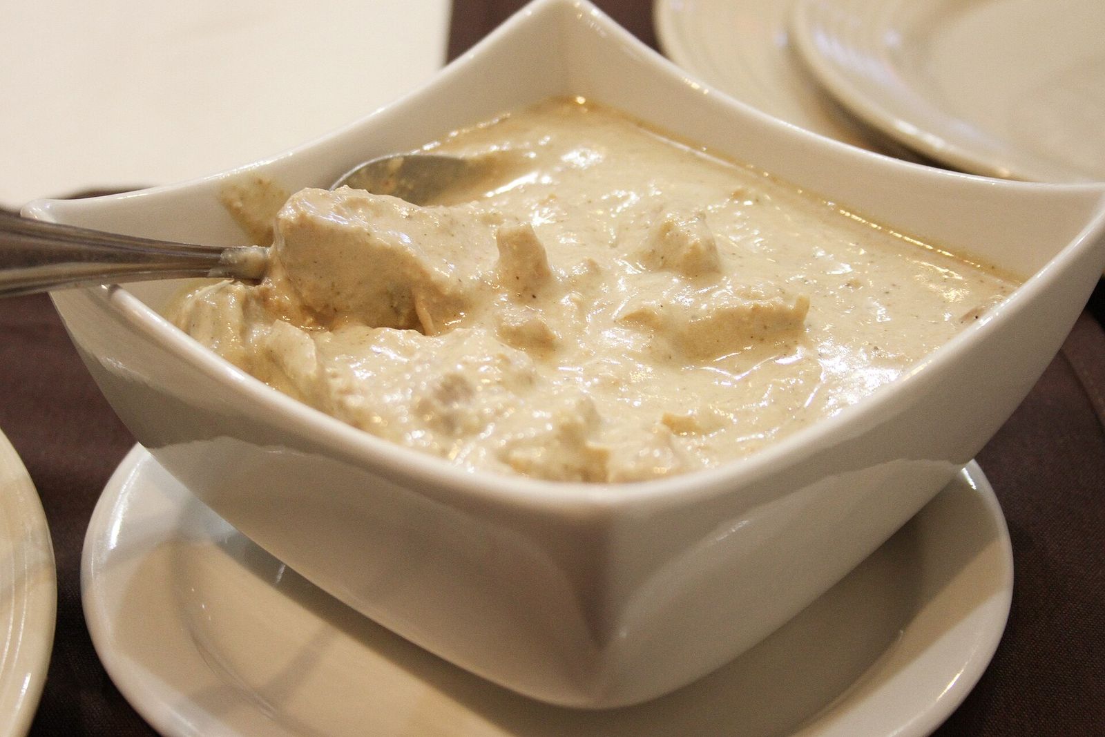 A bowl of satsivi, chicken pieces in a thick creamy walnut sauce