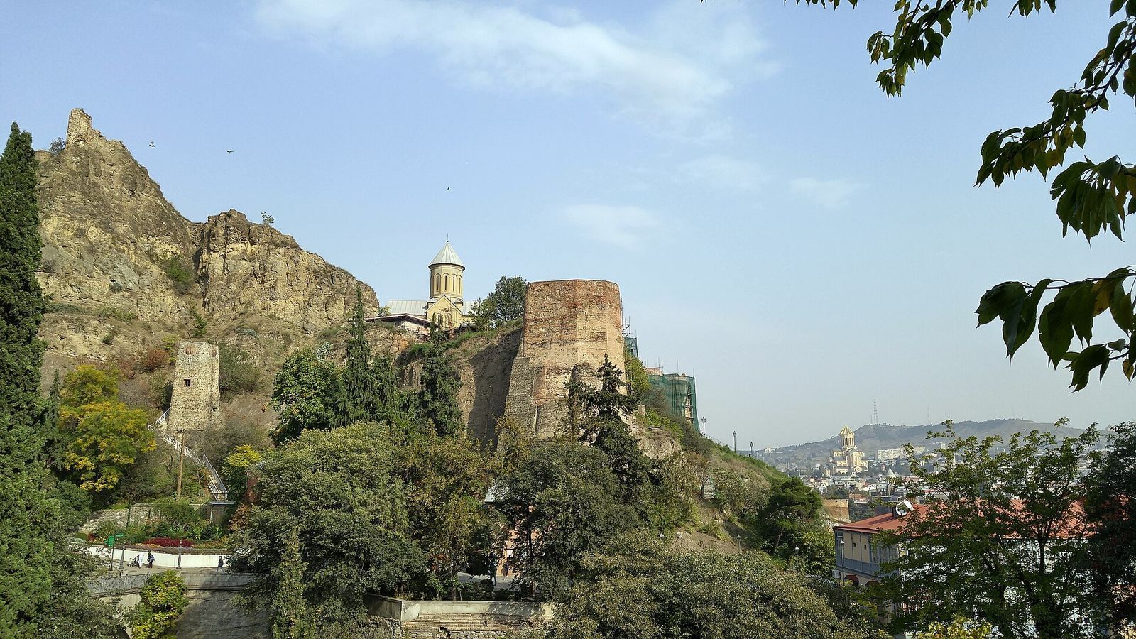 The National Botanical Garden of Georgia with its greenhouses, the walls of Narikala Fortress and St Nicholas Church on the ridge above