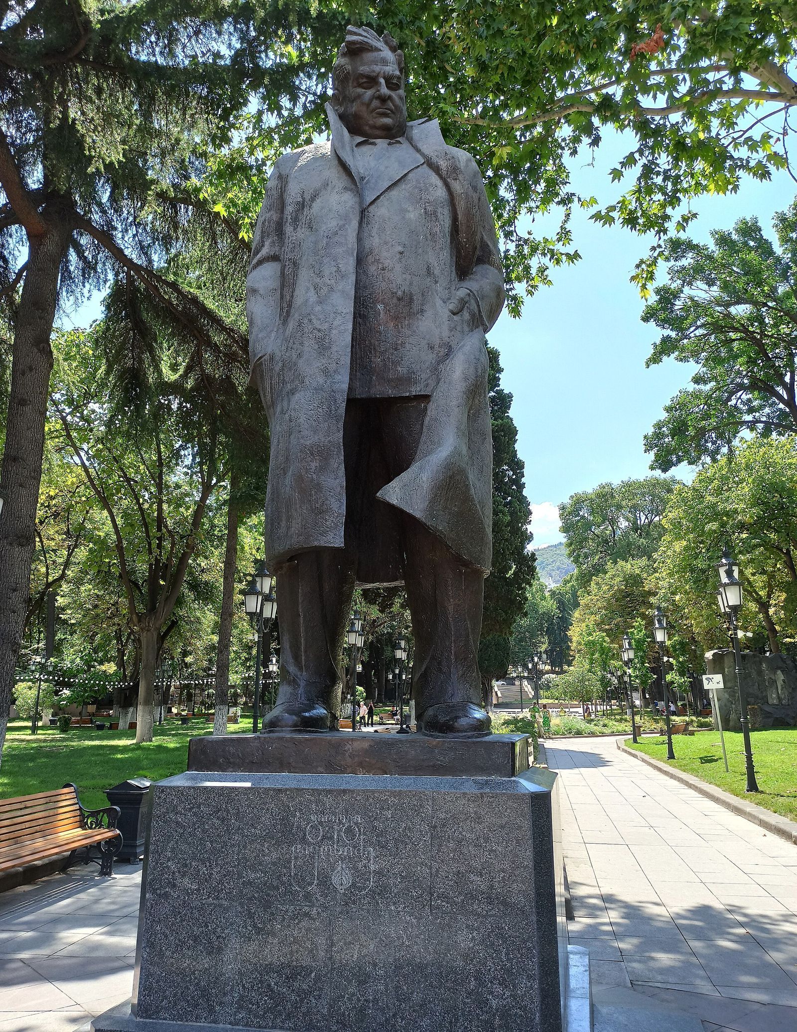 The bronze statue of the poet Giorgi Leonidze among plane trees and lamp-lined paths in Leonidze Park