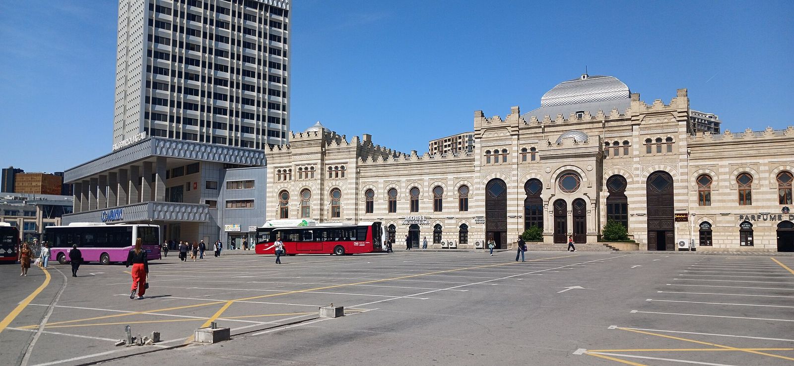 Baku Railway Station, a cream stone building with arched entrances, with red city buses parked in the square in front