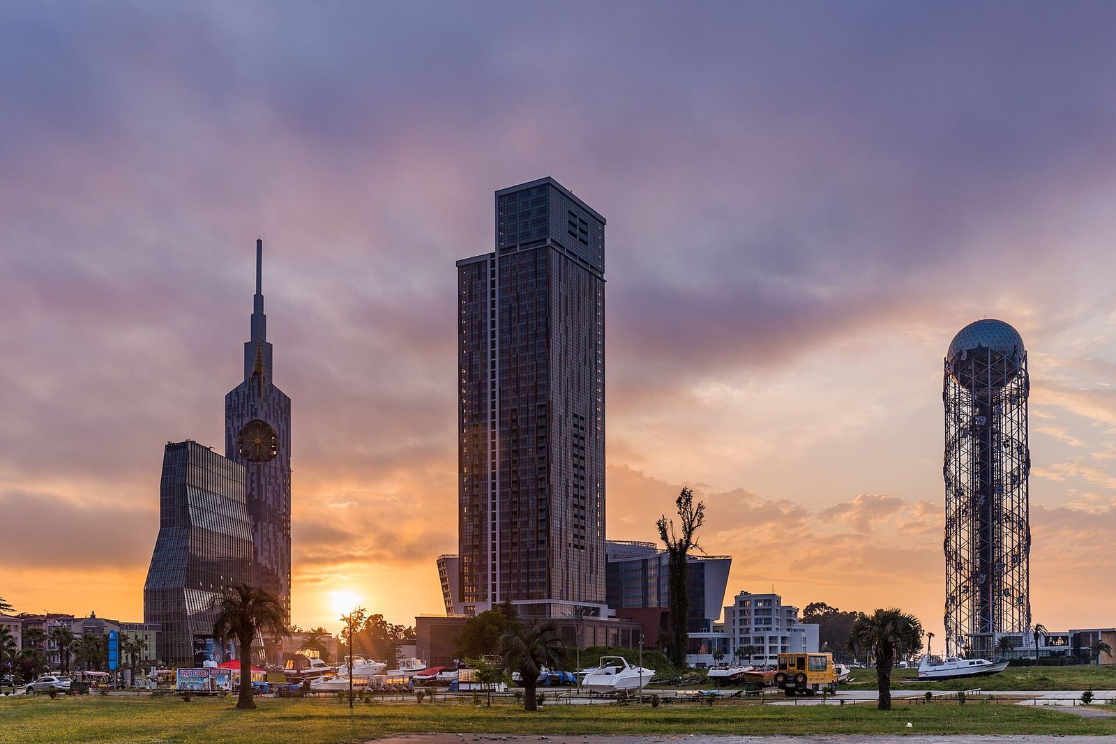 The towers of New Batumi and the Alphabet Tower at sunset, with palm trees in front