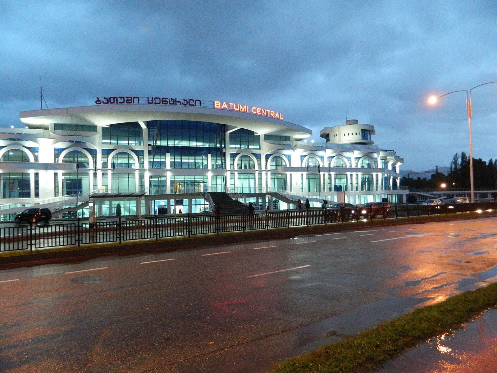Batumi Central railway station lit up at dusk, with its name in Georgian and English on the roof