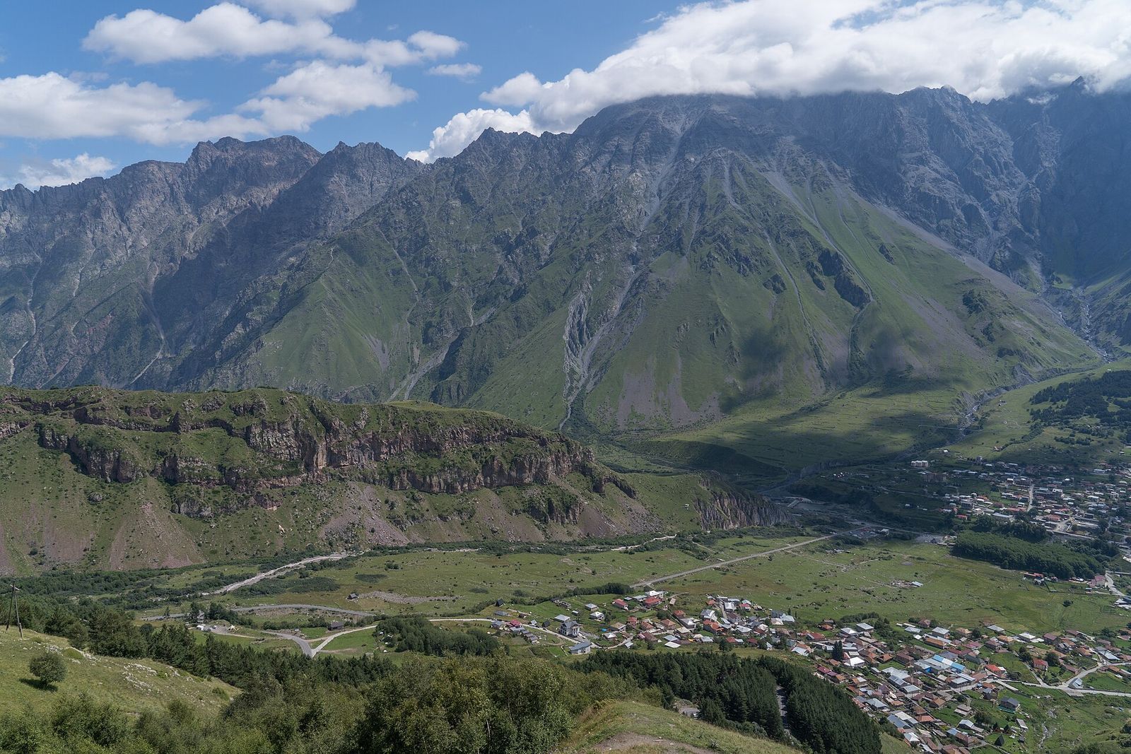 The houses of Stepantsminda in the valley below the Gergeti ridge, with mountains rising behind the town
