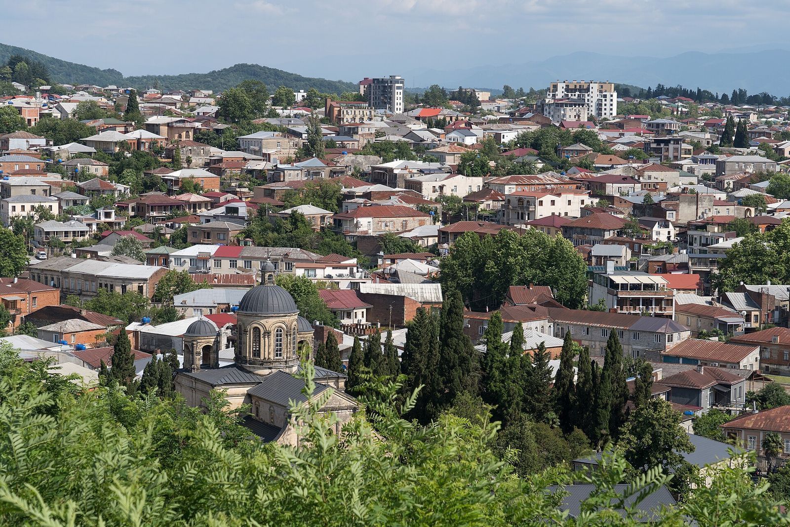 Rooftops of Kutaisi spread along the Rioni river valley under green hills