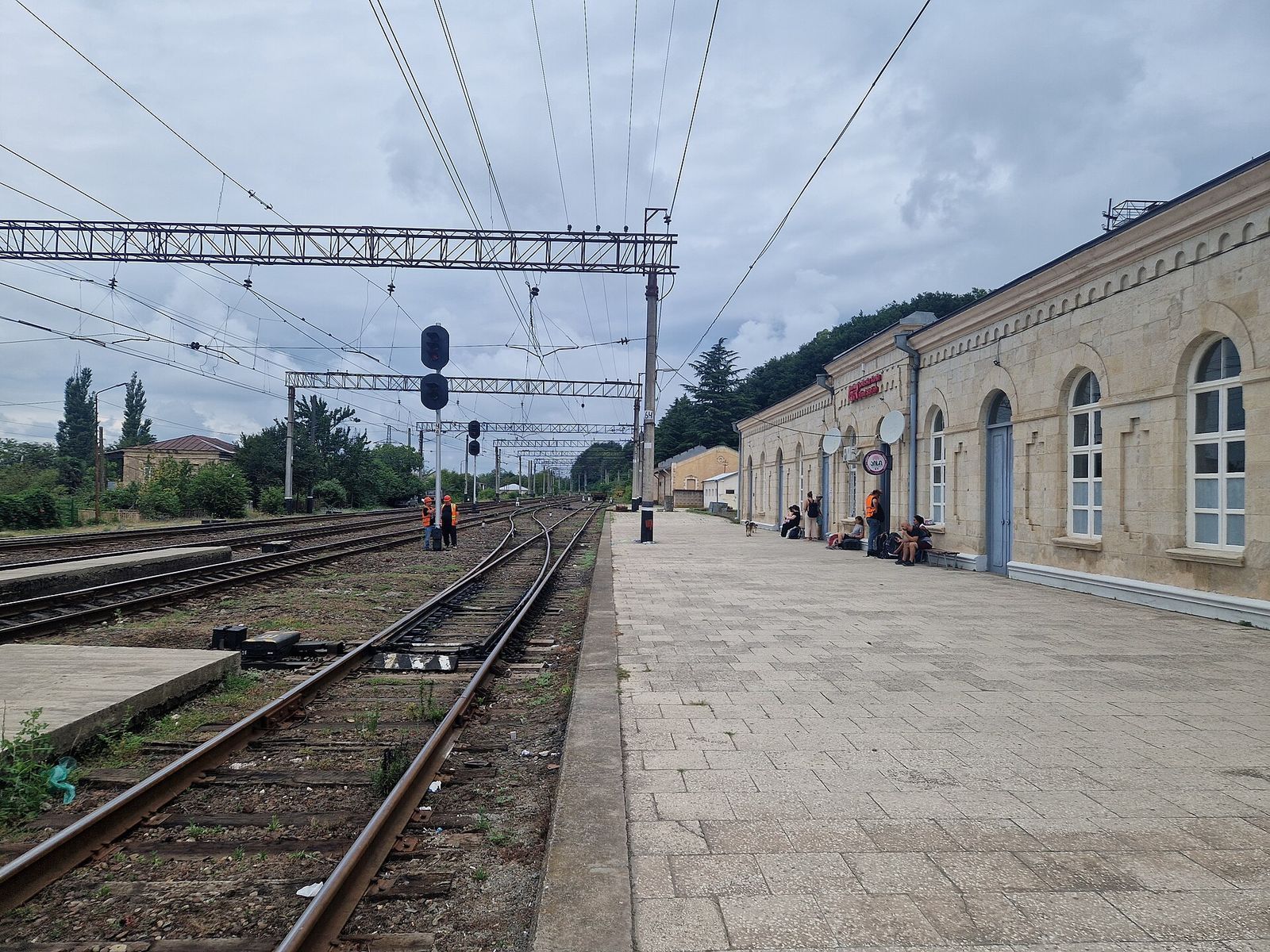 The platform and pale stone station building at Rioni railway station outside Kutaisi, with the tracks running past