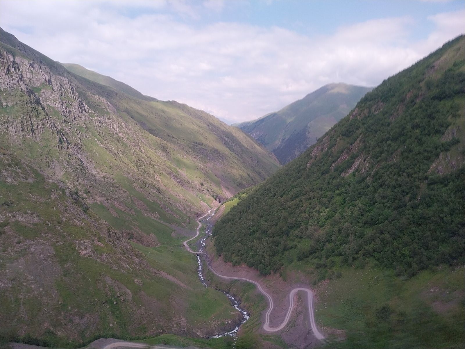 The dirt road from the Abano Pass to Omalo zigzagging down a steep green valley in Tusheti