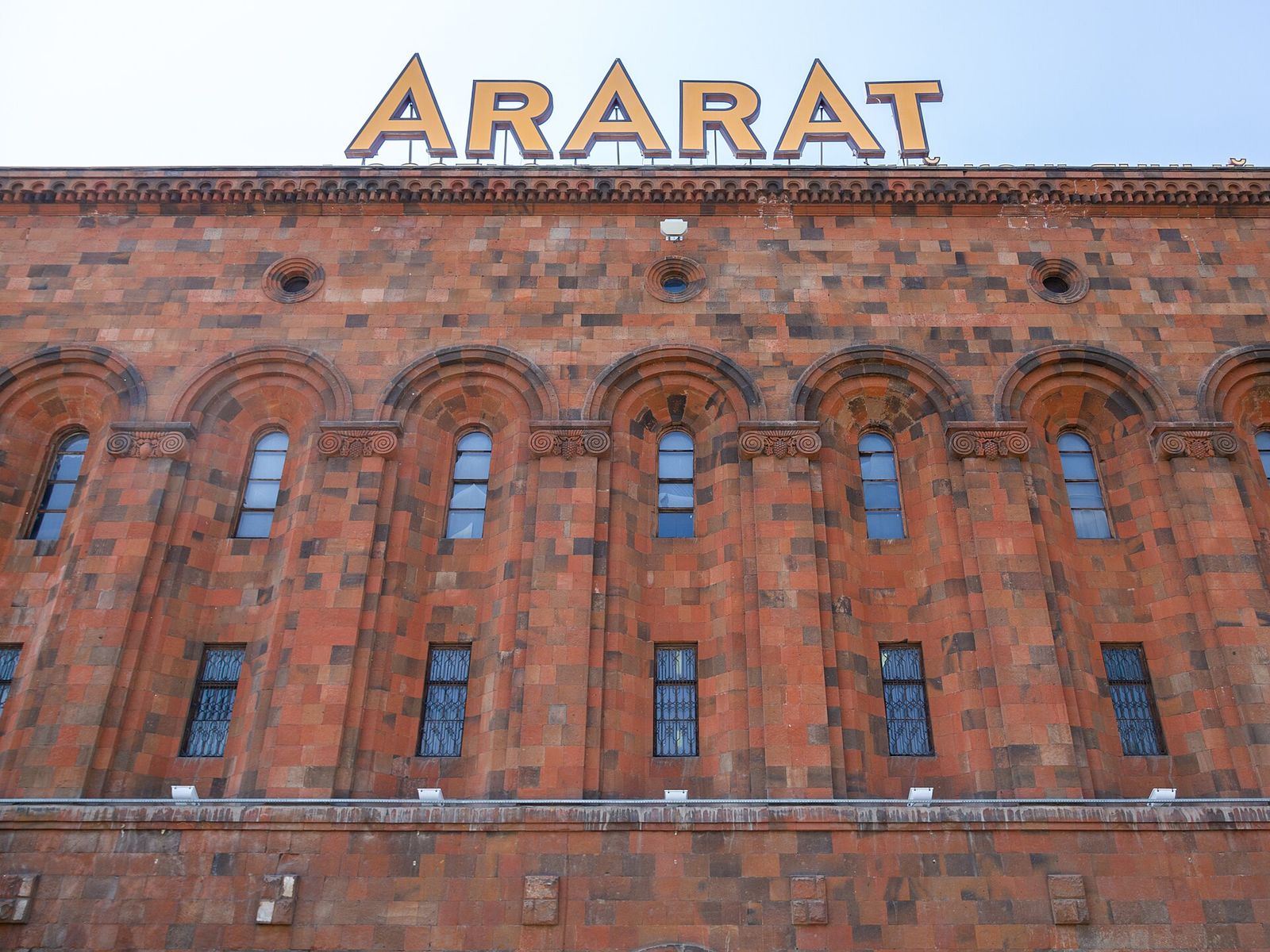 The red stone facade of the Ararat brandy factory in Yerevan with its rooftop ARARAT sign