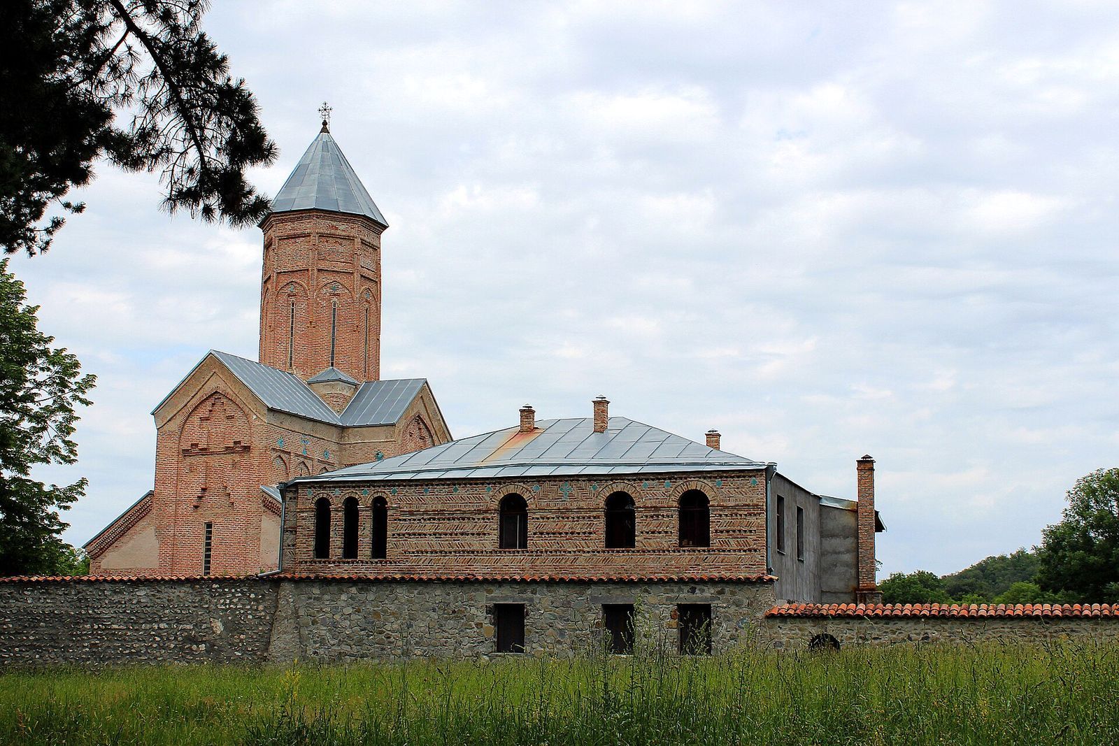 The tall brick church of New Shuamta convent rising behind the convent's stone wall and two-story brick building