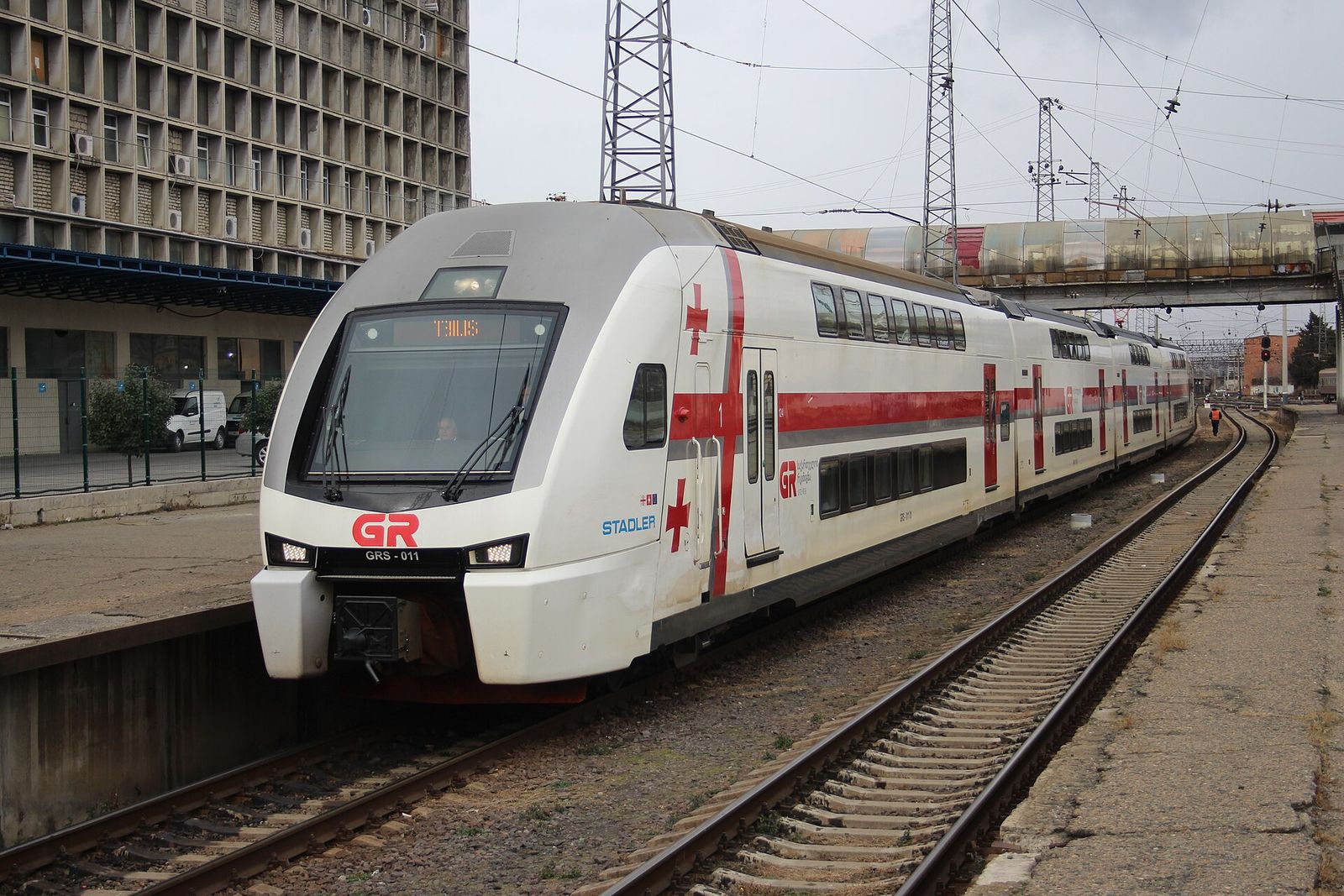 A white and red Georgian Railway Stadler double-decker train arriving at Tbilisi after a run from Batumi