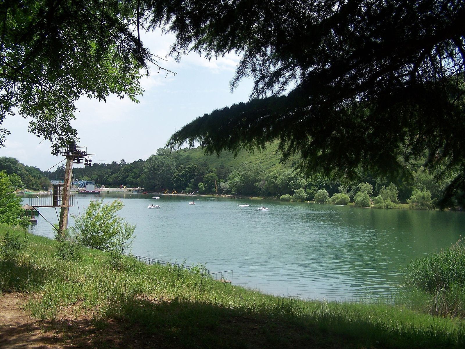 Paddle boats on Turtle Lake with the zip line tower on the left shore and forested hills behind