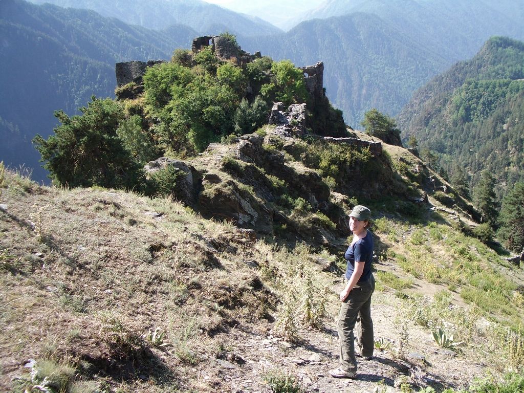 A hiker on the path out to the ruined walls of Diklo fortress, on a tree-covered rock spur above deep forested valleys