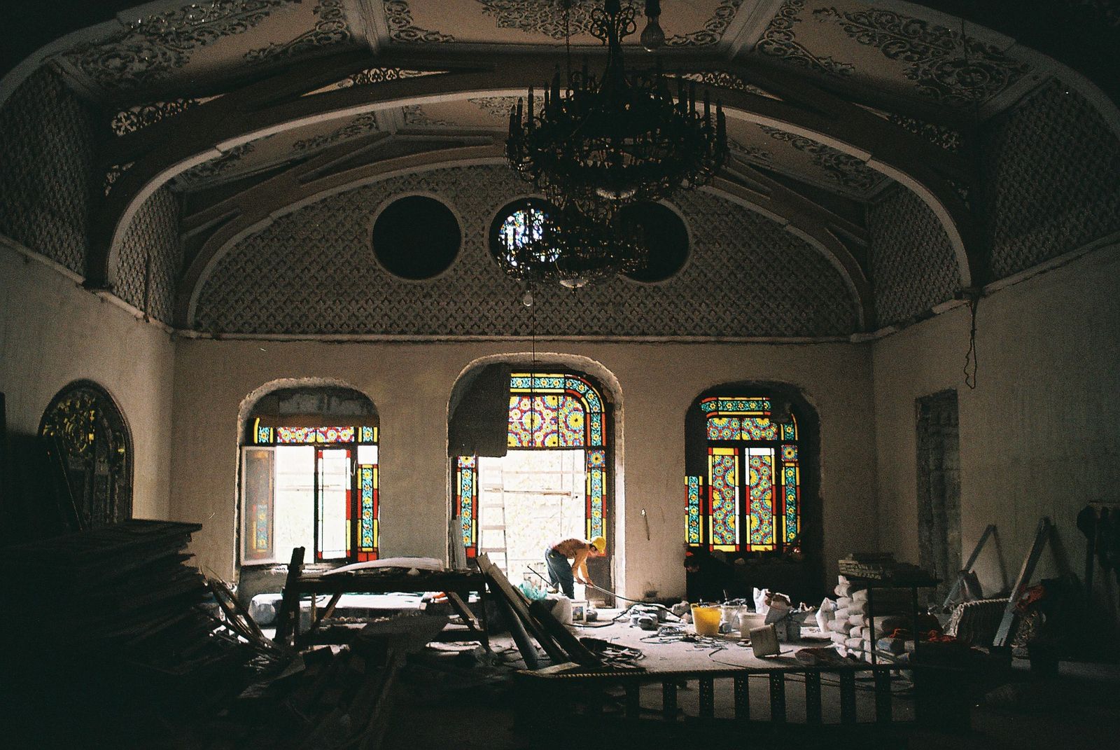 A hall of the Tbilisi Academy of Arts during restoration, with stained-glass windows, a chandelier and a painted vaulted ceiling