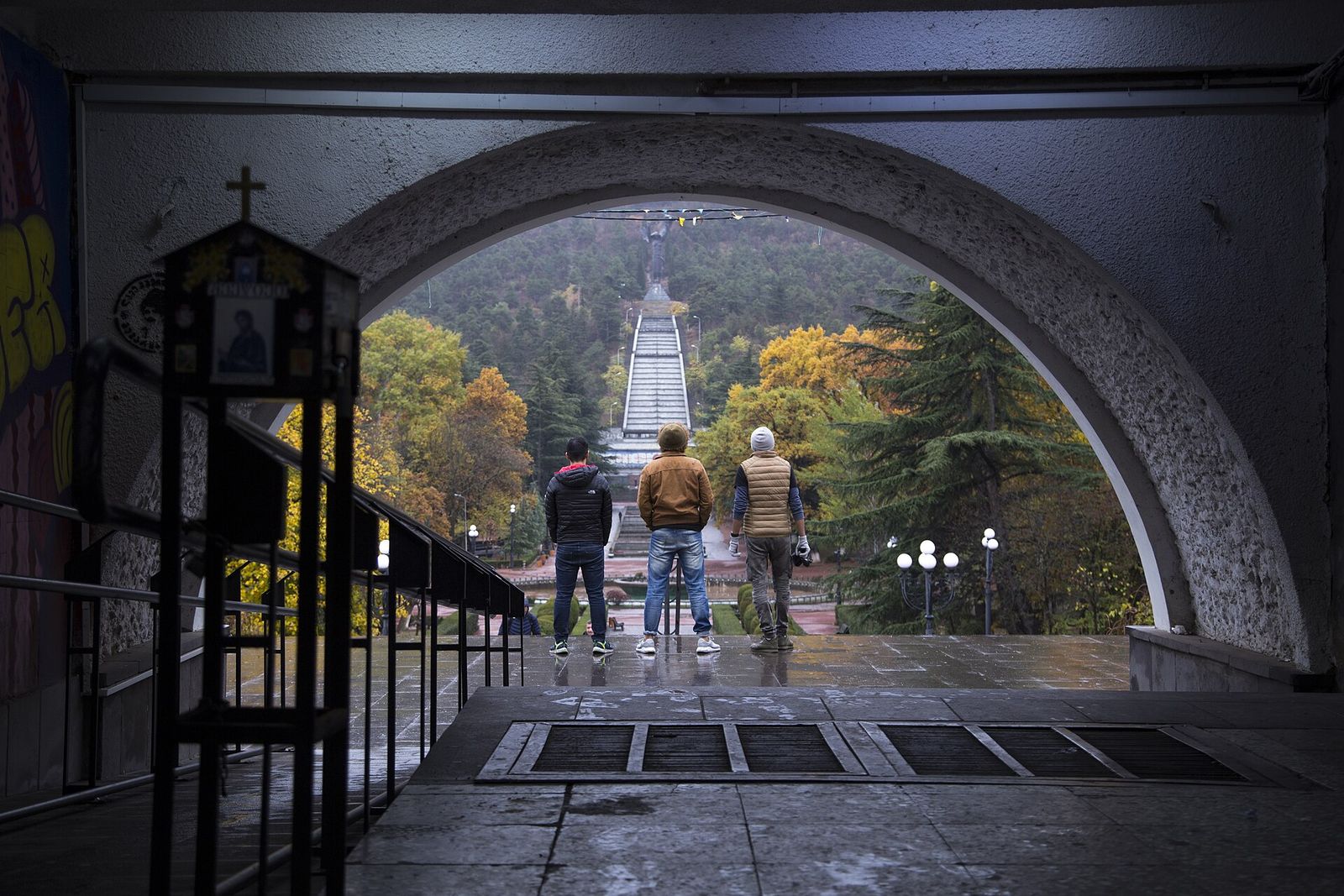 Visitors looking up the long cascade staircase of Vake Park through an arch, with autumn trees on both sides