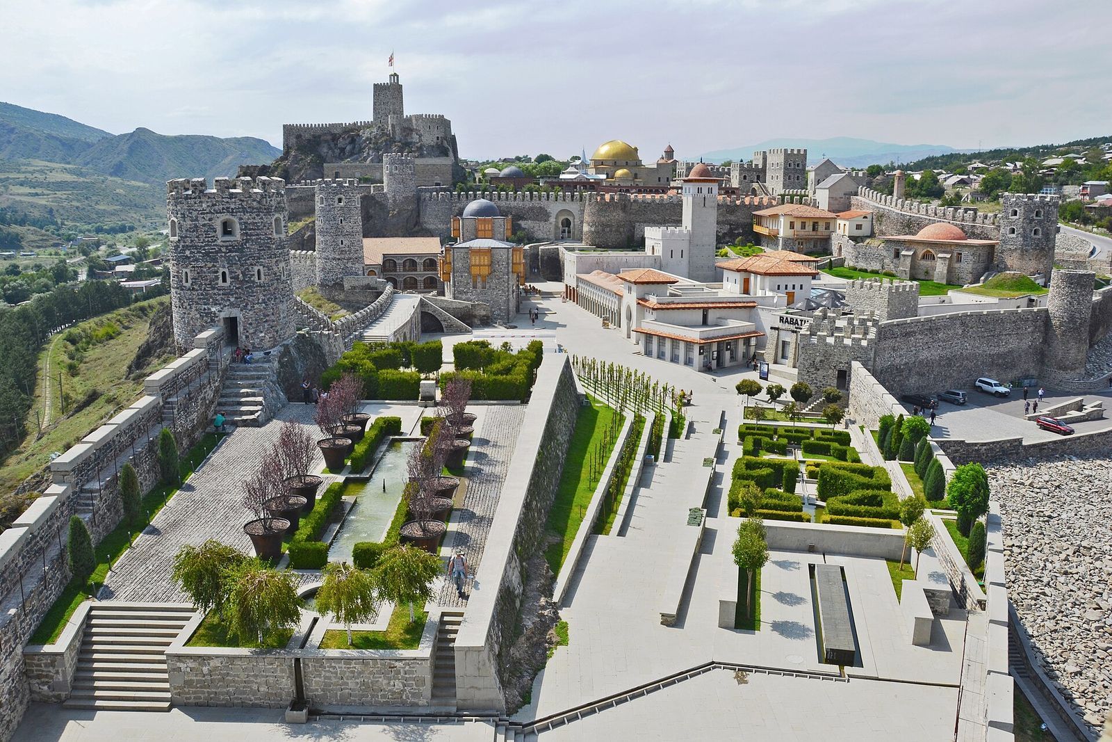 Rabati Castle in Akhaltsikhe from above: stone towers and walls, a gold-domed mosque and terraced gardens with a pool