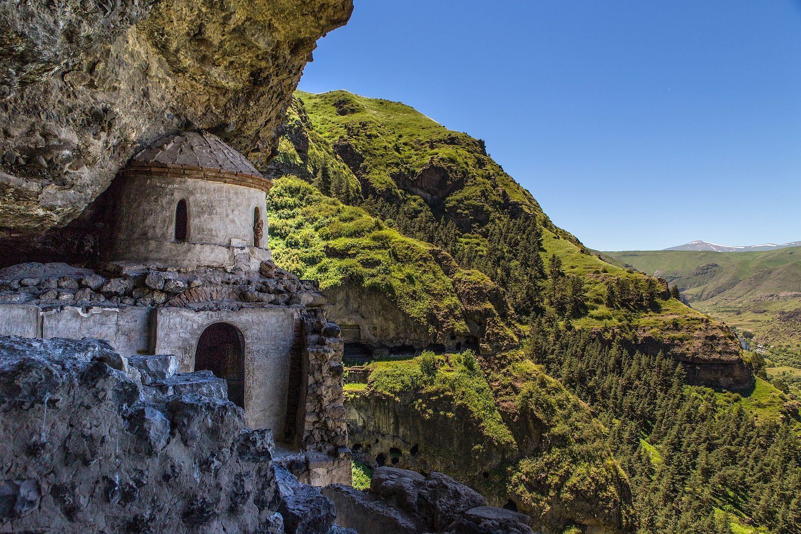 The small domed church of Vanis Kvabebi tucked under a rock overhang above the green Mtkvari gorge