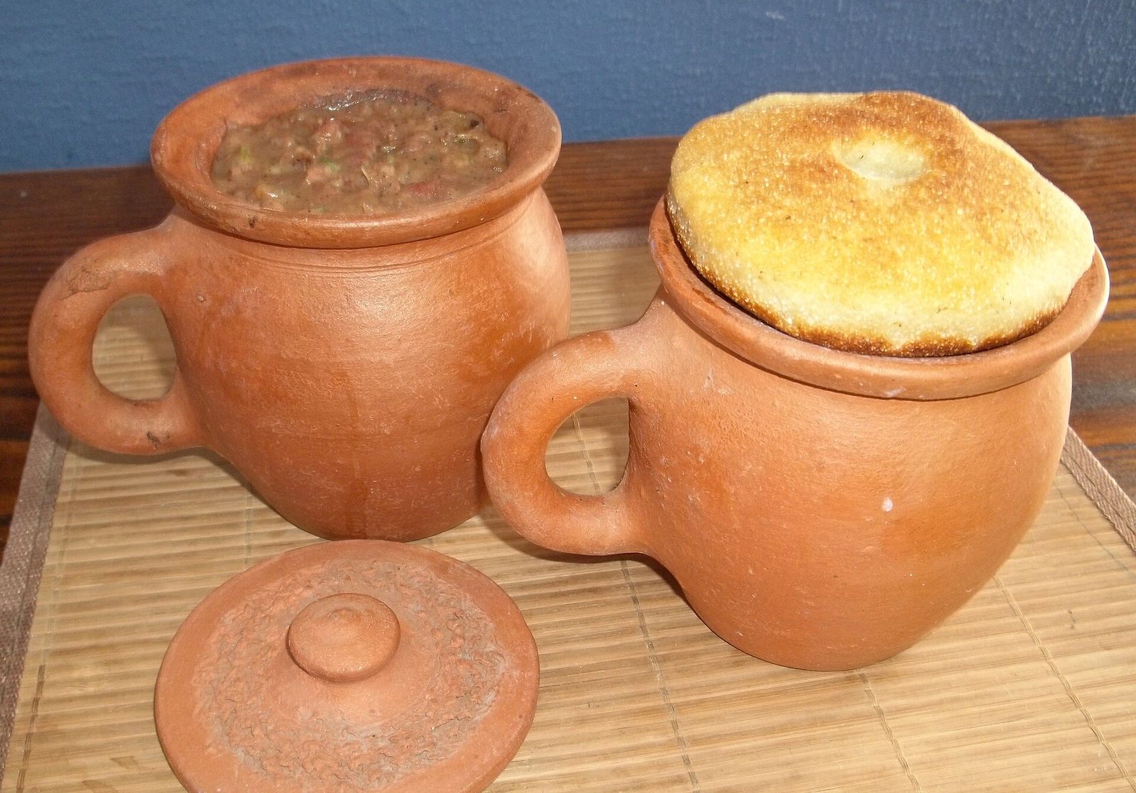 Lobio in clay pots, one of them topped with a round of mchadi cornbread