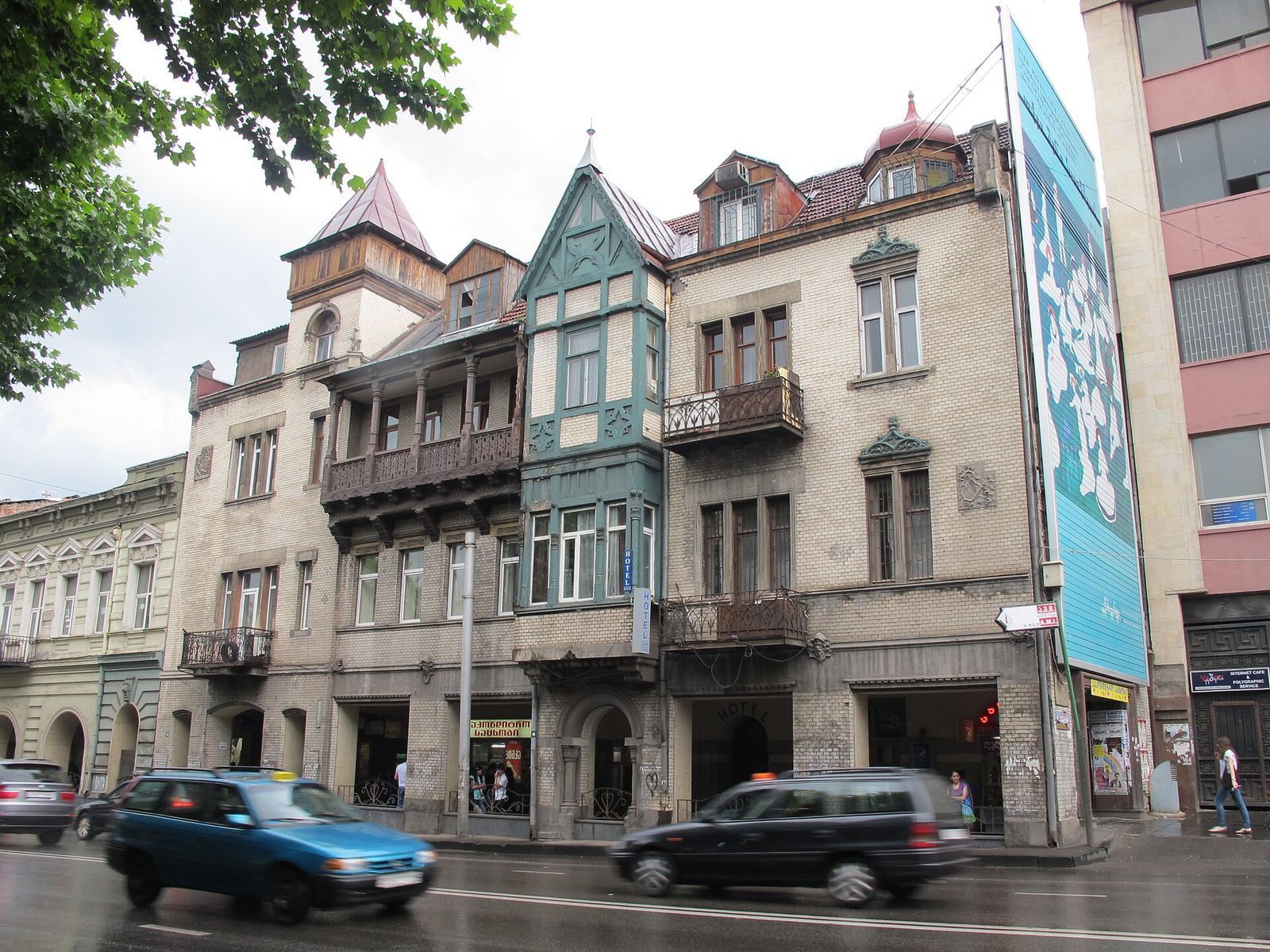 Art Nouveau house at 12 Merab Kostava Street with a pointed corner tower, a carved wooden gallery and a green half-timbered bay