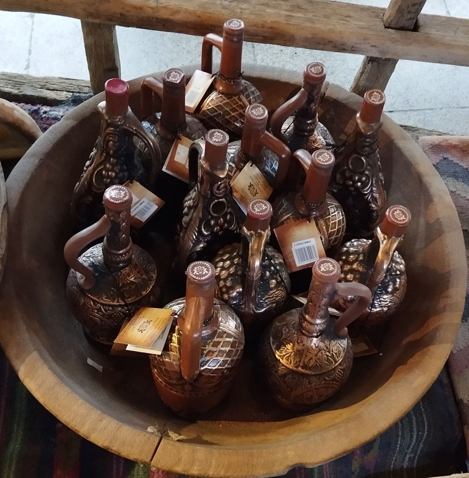 Ornate clay wine bottles with handles in a wooden bowl at the Meidan bazaar in Tbilisi
